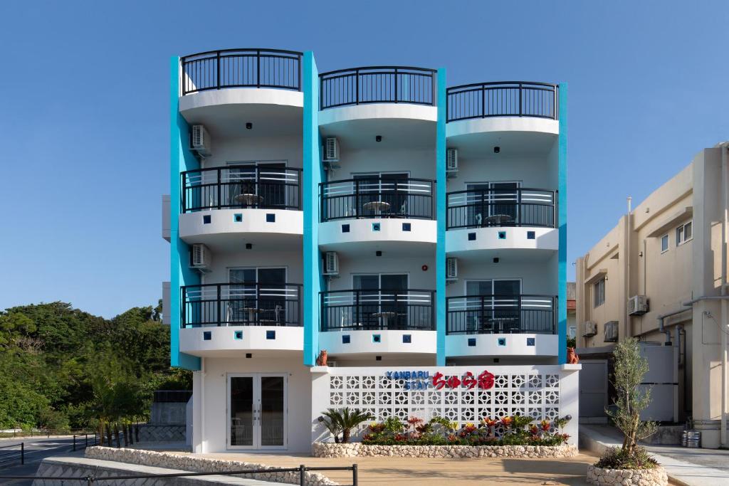 名户YANBARU STAY ちゅら宿的带阳台的蓝白色公寓大楼