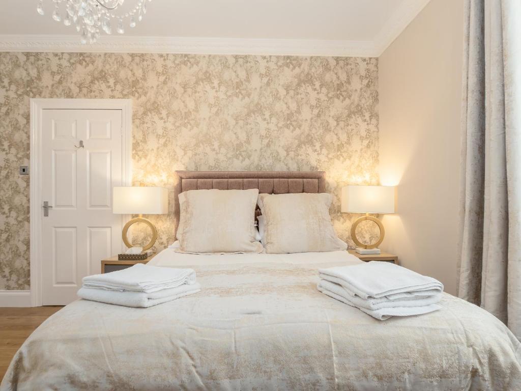 桑德兰Sunderland Self Catering 2 - Violet Cottage Free Parking的一间卧室配有一张带两盏灯的大型白色床。