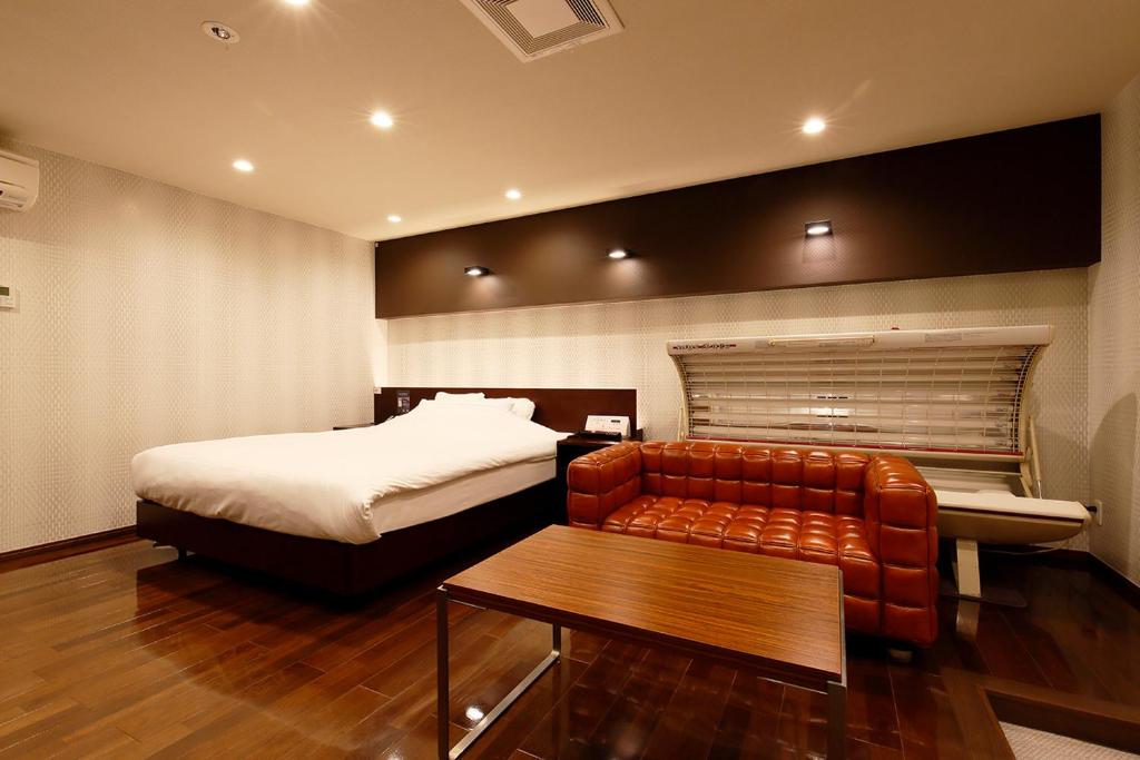 HigashineHOTEL 555 Air的一间卧室配有一张床、一张沙发和一张桌子