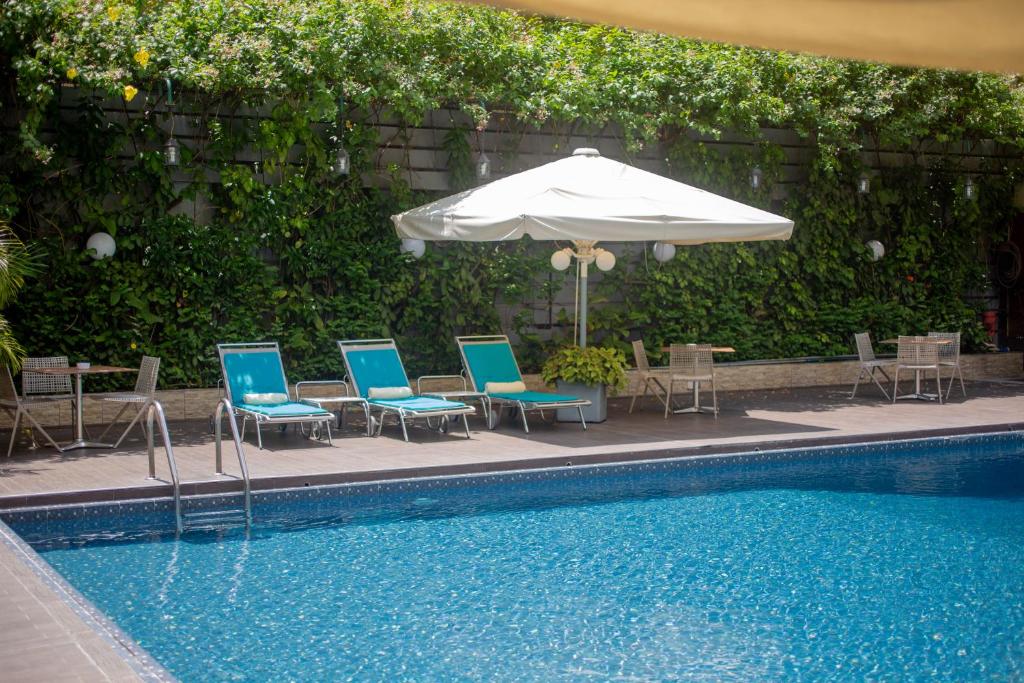 金沙萨梅美灵酒店的一组椅子和一把遮阳伞,位于游泳池旁