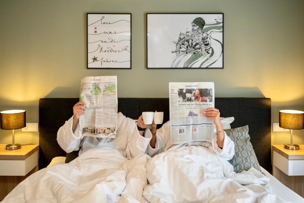 耶弗尔Stadthotel Jever的躺在床上阅读报纸的人