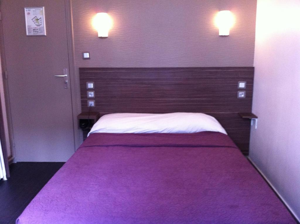 巴黎格兰德酒店的一间卧室配有一张大床和紫色毯子
