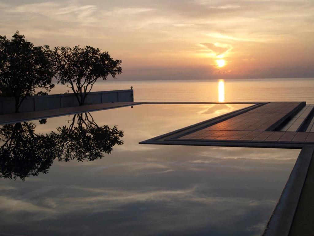 卡农2-Bedroom Khanom Beach Ocean Front Condo的一座享有日落美景的游泳池