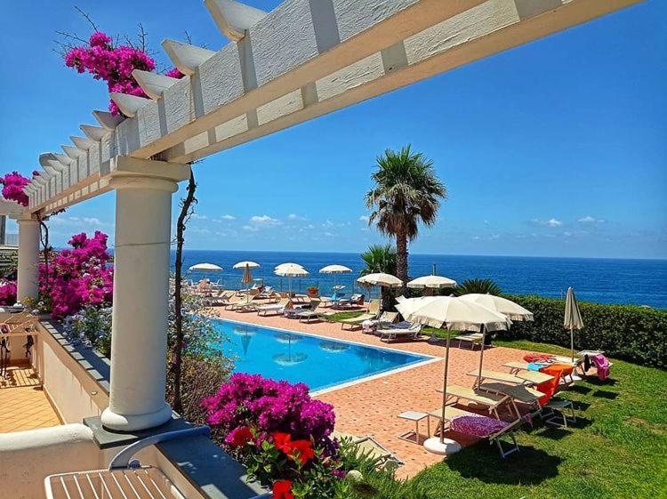 伊斯基亚奥巴特瑞酒店的一个带遮阳伞和椅子的游泳池以及大海