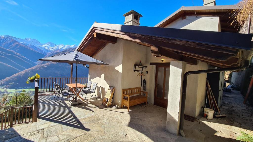 Villar PelliceIndependent chalet with breathtaking view的一个带桌子和遮阳伞的房屋阳台
