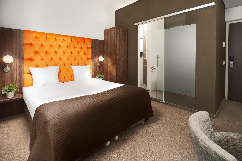 埃因霍温拉雷因酒店的一间卧室配有一张大床和一把椅子