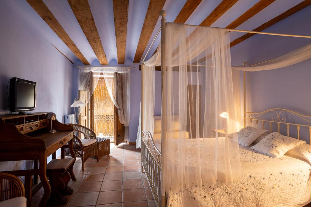Talayuelas拉卡萨格兰德酒店的一间卧室配有一张天蓬床和一架钢琴