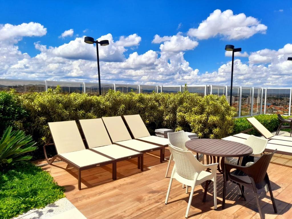 瓜鲁柳斯Via Alameda Studio 706 -GRU-的庭院设有白色的椅子和一张桌子,享有美景。