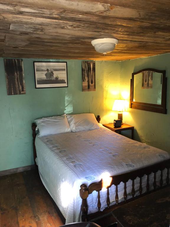 旧奥查德比奇海员宾馆和别墅的一间卧室设有一张带木制天花板的大床