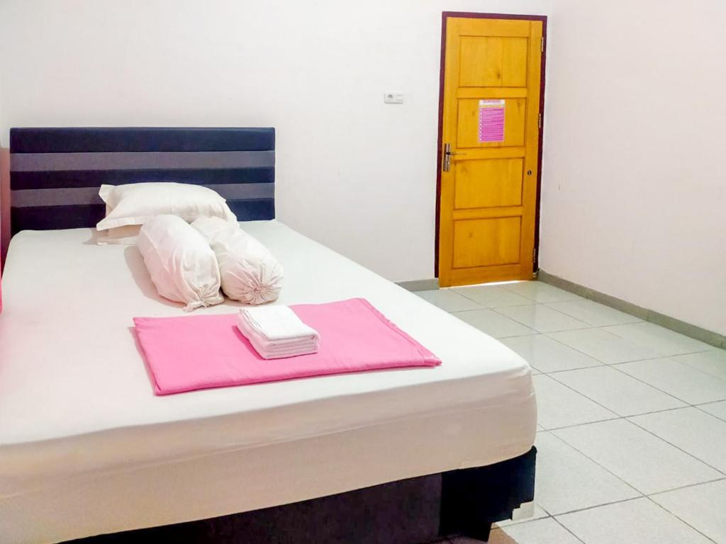 PosoRedDoorz @ Makarios Hotel Poso的一间卧室配有带粉红色毛巾的床