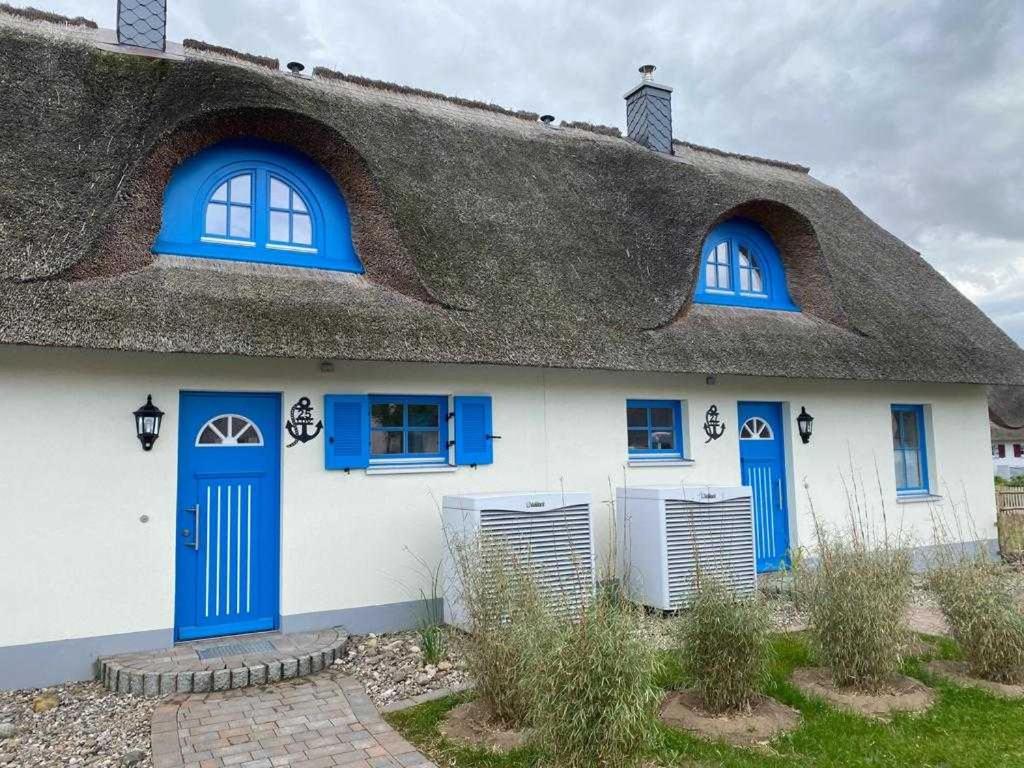 齐罗Ferienhäuser Luv und Lee OVS 106 Neu 20的白色的房子,设有蓝色的窗户和茅草屋顶