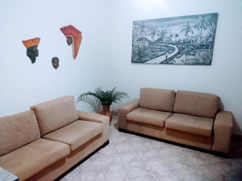 伦索伊斯Pousada e Hostel Chapada Suites的客厅配有两张沙发,墙上挂有绘画作品