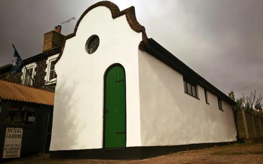 布兰登Old Fire Station - quaint and quirky little home的一座白色的小建筑,设有绿门