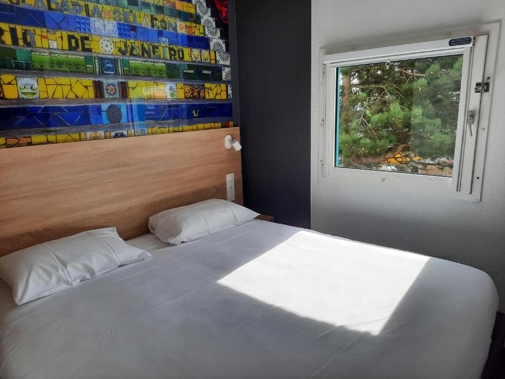 凯恩Kyriad Direct Caen Nord Memorial的卧室配有白色的床和窗户。