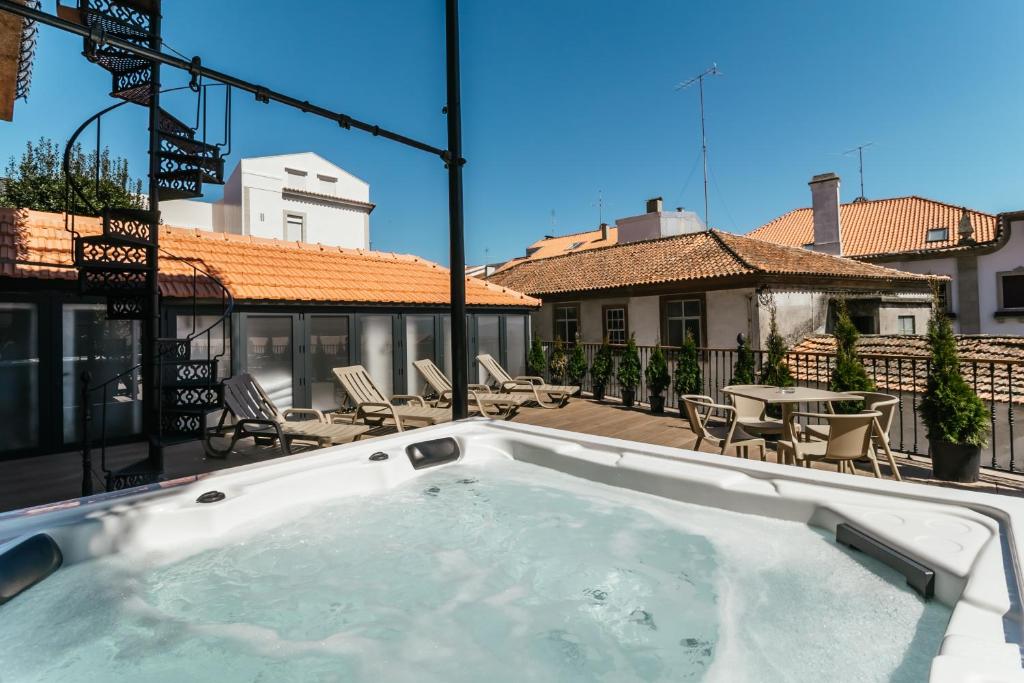 科维良Royal Collection Covilhã的阳台设有热水浴池、椅子和桌子