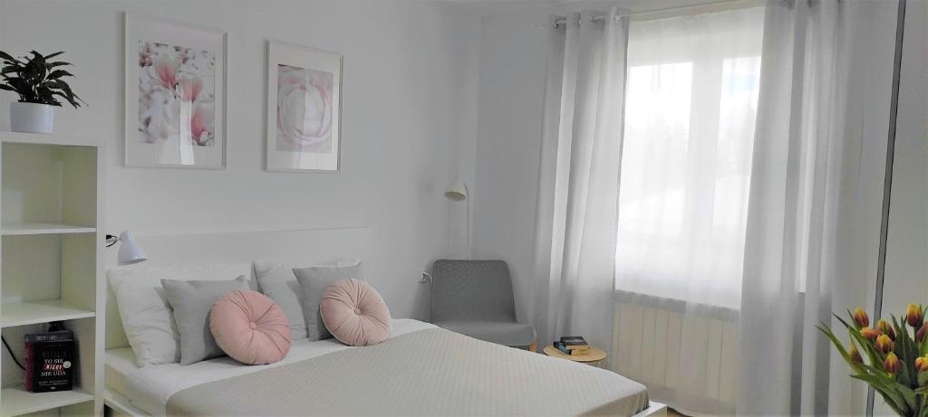 维伦匝布赞斯基Domowa- Restauracja i Pokoje的卧室配有白色床、粉红色枕头和窗户