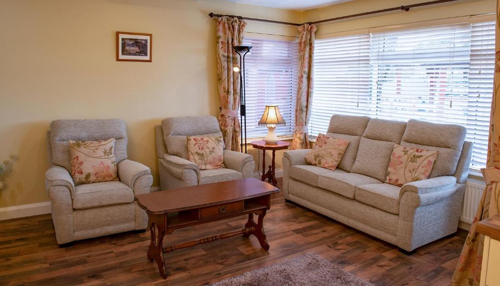 布什米尔斯Causeway Lodge的客厅配有两把椅子、一张沙发和一张桌子