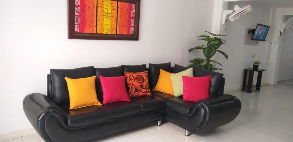 托卢Hostal Girasoles Tolu的黑色皮革沙发,上面有色彩缤纷的枕头