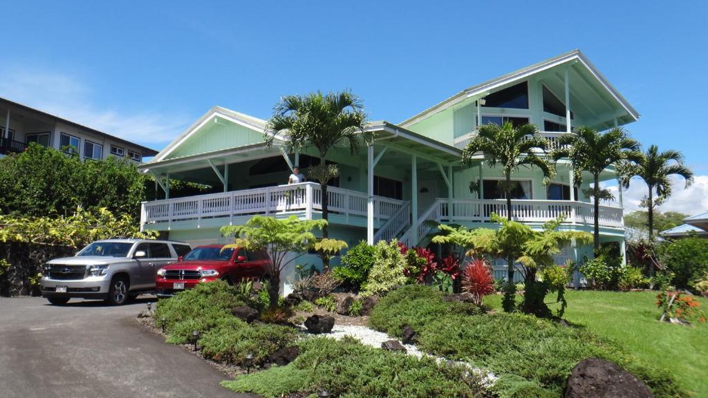 希洛GUEST HOUSE IN HILO的一座绿色房子,前面停有汽车