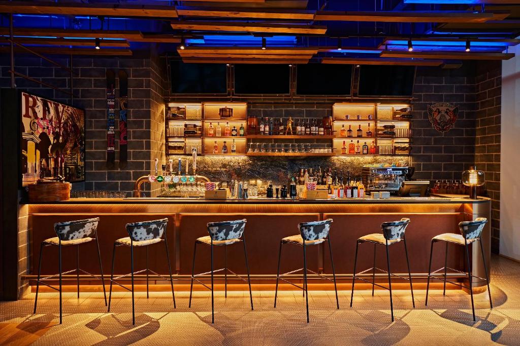 迪拜Revier Hotel - Dubai的砖墙前有凳子的酒吧