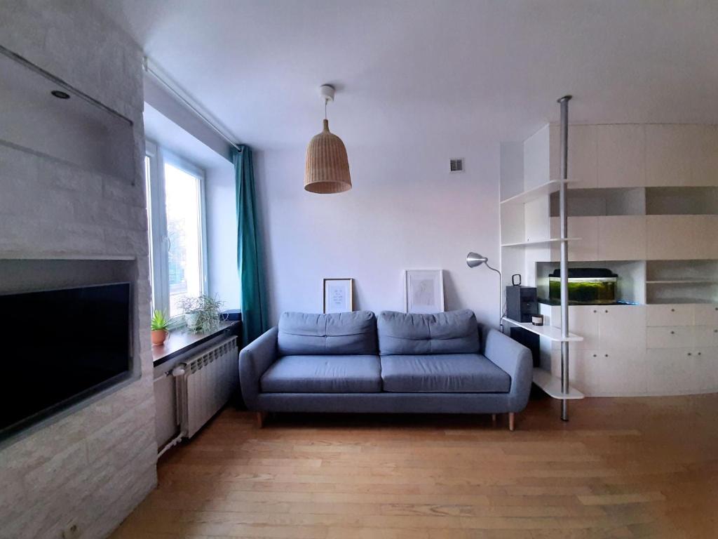 华沙Apartament Rokosowska的客厅配有蓝色的沙发和电视