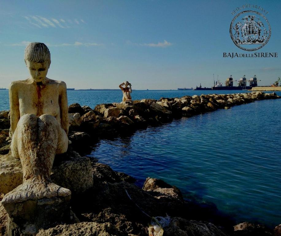 塔兰托Baja delle Sirene的水边摇滚的男孩雕像
