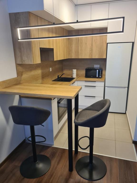 布达佩斯Aphrodité apartman的厨房配有2张吧台凳和1张木桌