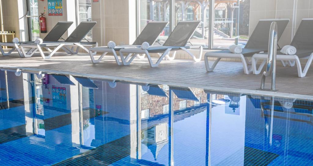 博尔顿最后一滴水乡村Spa酒店的水边带躺椅的游泳池