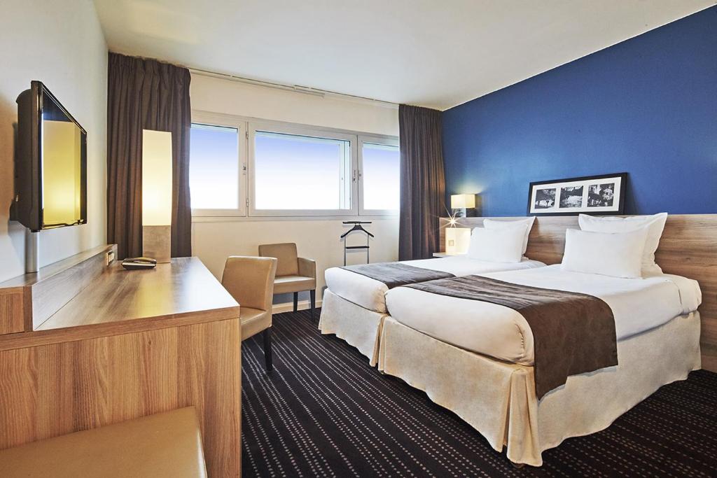 勒布尔热Campanile Le Bourget – Airport的酒店客房设有一张大床和一张书桌。