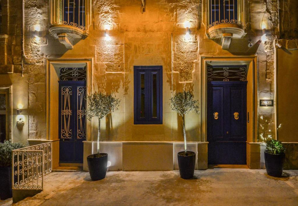 森格莱阿Senglea Suites的一座建筑,有两扇蓝色的门和两棵盆栽植物
