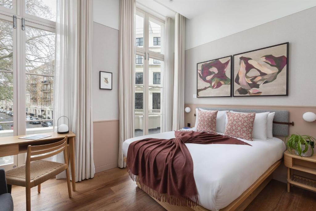 伦敦Inhabit Queen's Gardens, a Member of Design Hotels的卧室配有一张床、一张书桌和窗户。