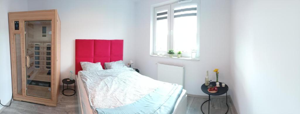 拉多姆Apartament z Sauna i Jacuzzi的一间卧室配有一张红色床头板的床