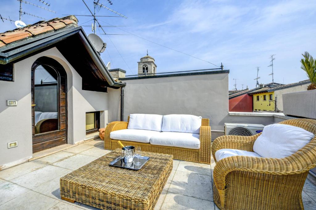 西尔米奥奈Prestige Suite Sirmione的阳台设有带藤椅和沙发的庭院