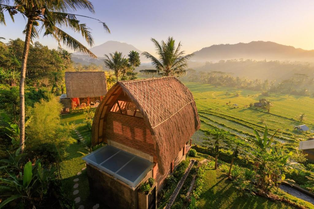 希德门Like living in a romantic Balinese painting的田野上草屋顶的小房子