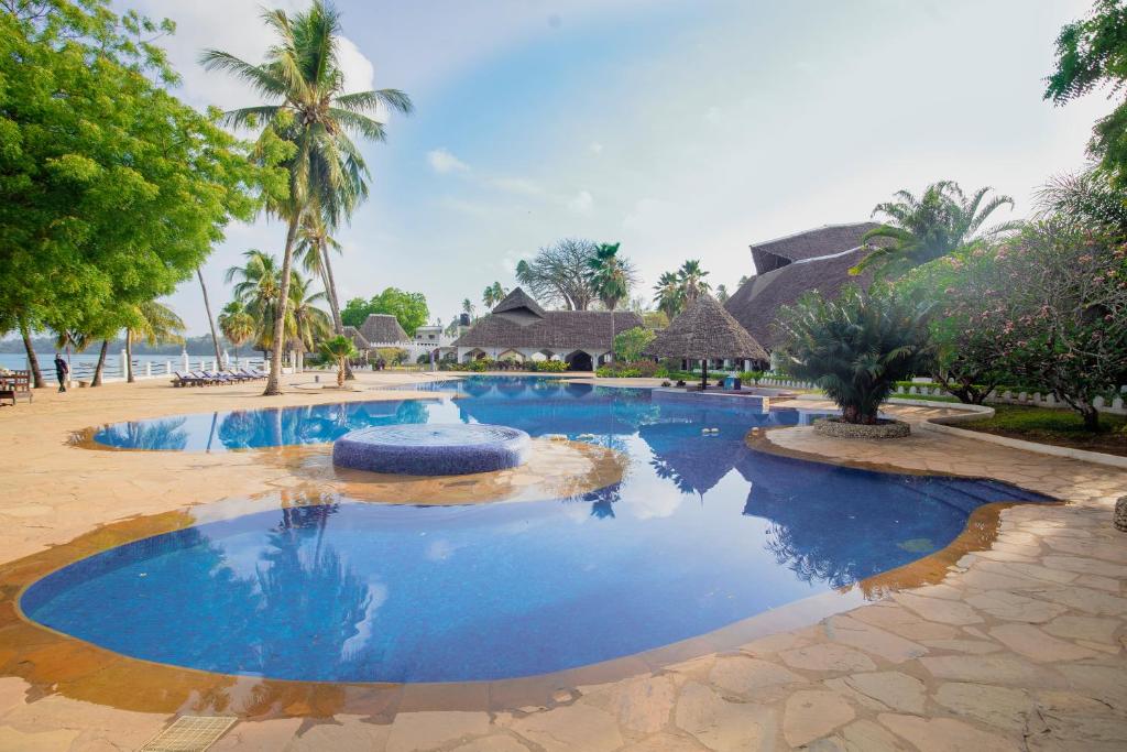桑给巴尔桑给巴尔海滩度假酒店的拥有蓝水和棕榈树的度假村的游泳池