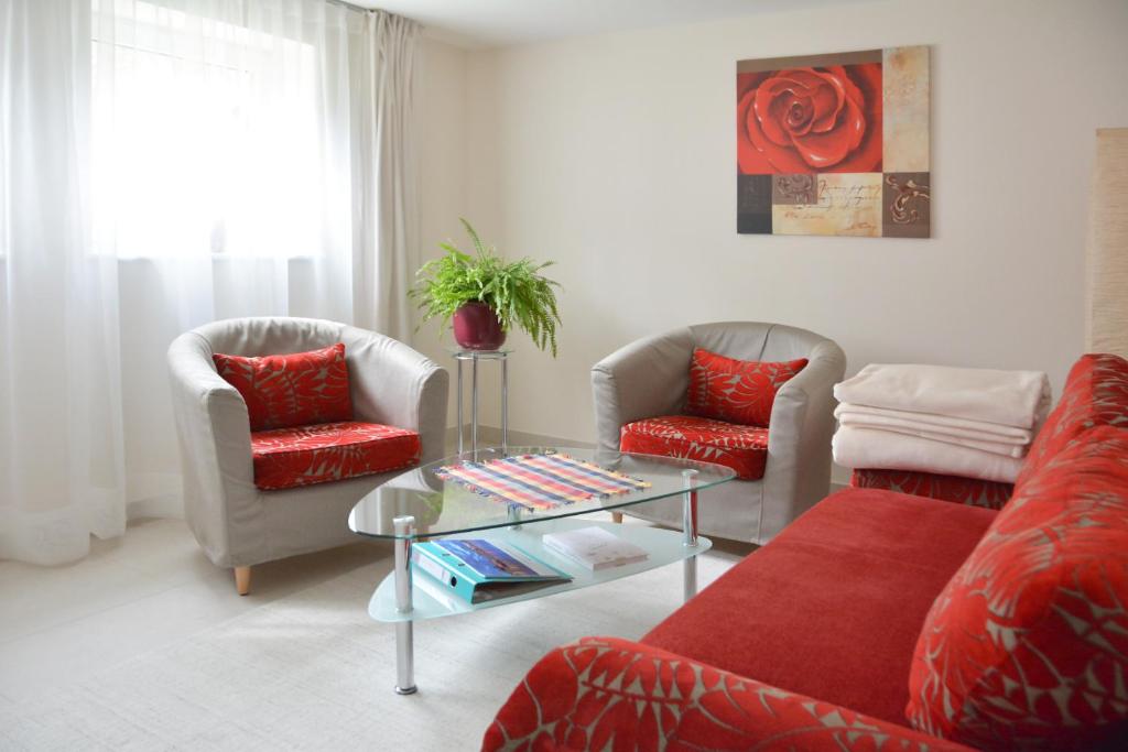 卡劳特格瑞斯赫Ferienwohnung Gohrisch的客厅配有两把椅子和一张红色沙发