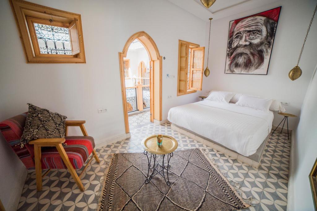 马拉喀什Riad Le Petit Joyau的卧室配有1张床、1张桌子和1把椅子