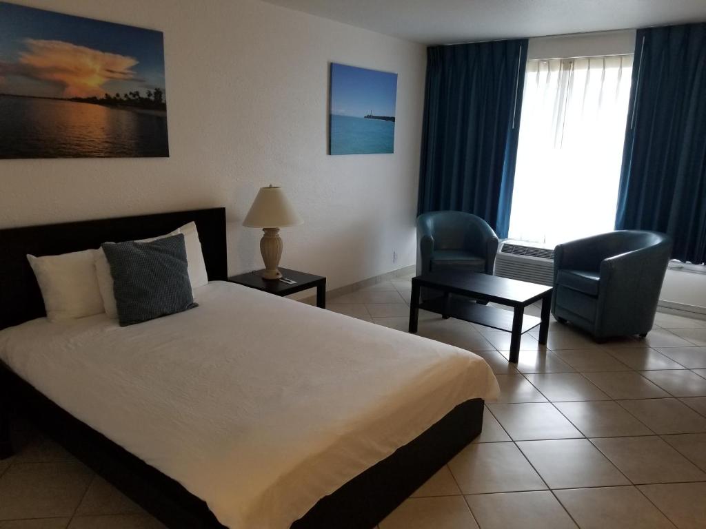 珊瑚角海豚钥匙度假酒店 - 珊瑚海角的酒店客房带一张大床和一把椅子