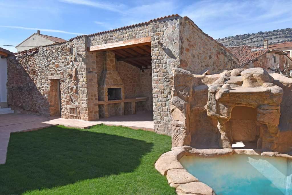 FuentetobaCasa Rural La Cueva del Agua的一座石头建筑,在院子里设有游泳池