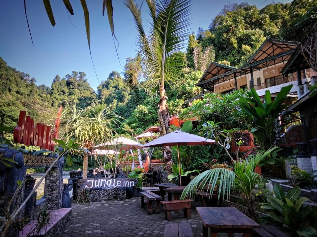 武吉拉旺Jungle Inn Bukit lawang的一个带桌子和遮阳伞的庭院。