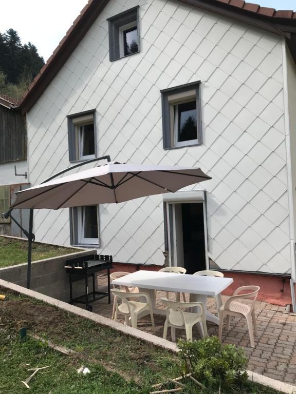 普兰凡Le Gîte du Petit Béret的房屋前的桌椅和遮阳伞