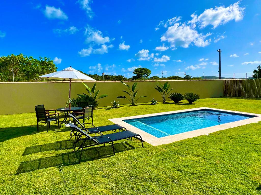 布希奥斯Private House Buzios - casa aluguel的后院设有游泳池、椅子和遮阳伞