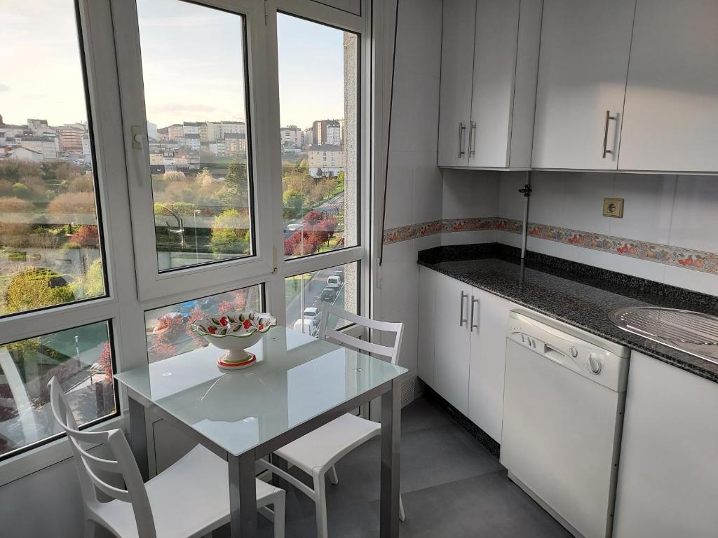 卢戈Apartamento Calzada Romana的厨房配有桌椅和窗户。