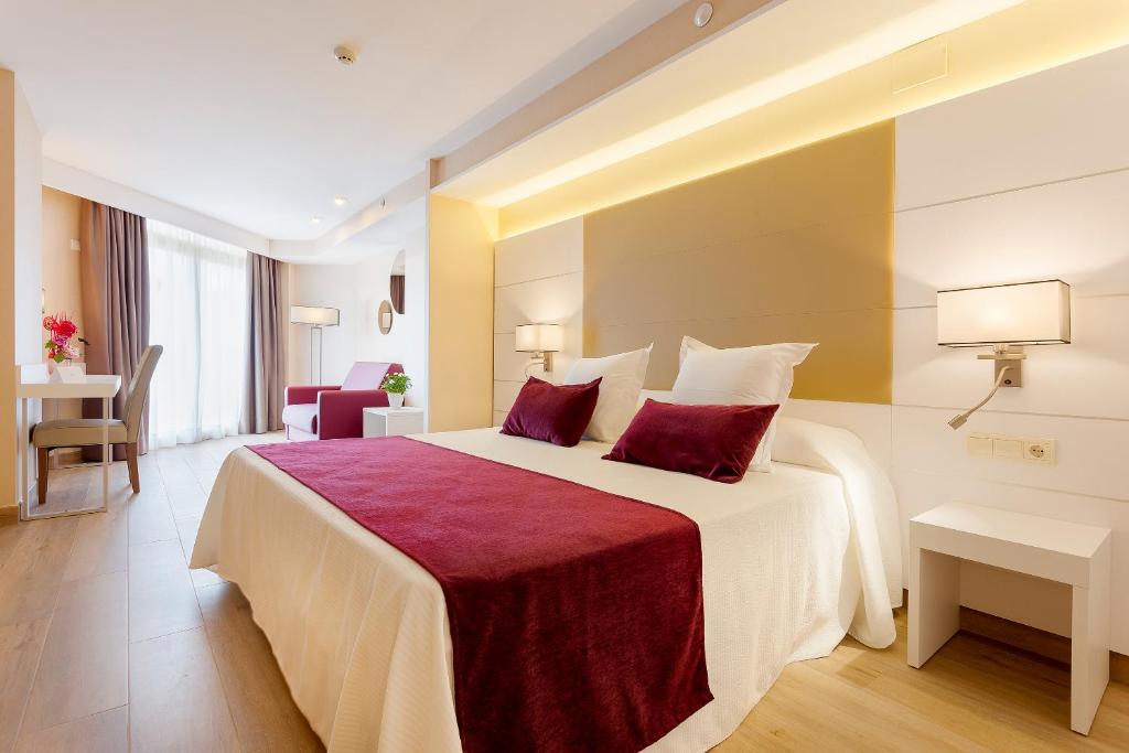 布拉内斯贝弗利公园酒店及水疗中心的酒店客房配有一张带红色枕头的大床
