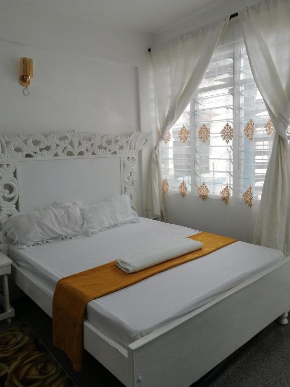 蒙巴萨Golden Nest的白色卧室设有一张带窗户的床