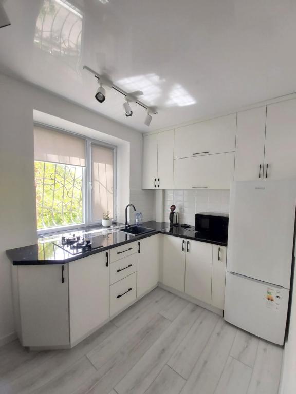 塔拉兹2-х комнатная квартира的厨房配有白色橱柜和白色冰箱。