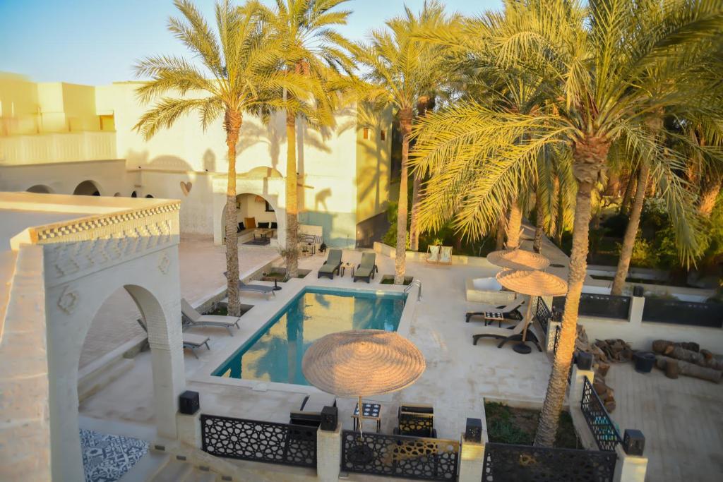 托泽尔Dar Yomma的一个带棕榈树和桌子的游泳池的度假酒店