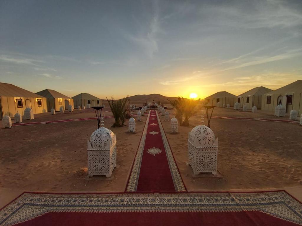 梅尔祖卡Luxury Desert Camp Amanar的一条在沙漠中的道路,伴随着日落