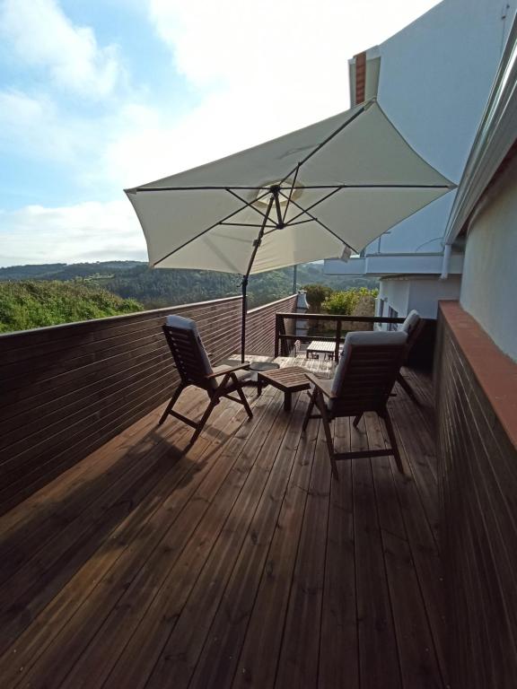 奥比多斯Refúgio da Sancheira Grande的庭院配有两把椅子、一张桌子和一把遮阳伞
