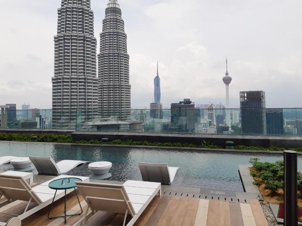 吉隆坡Star Luxury Suites KLCC的一个带椅子的屋顶露台和一个享有城市天际线的游泳池